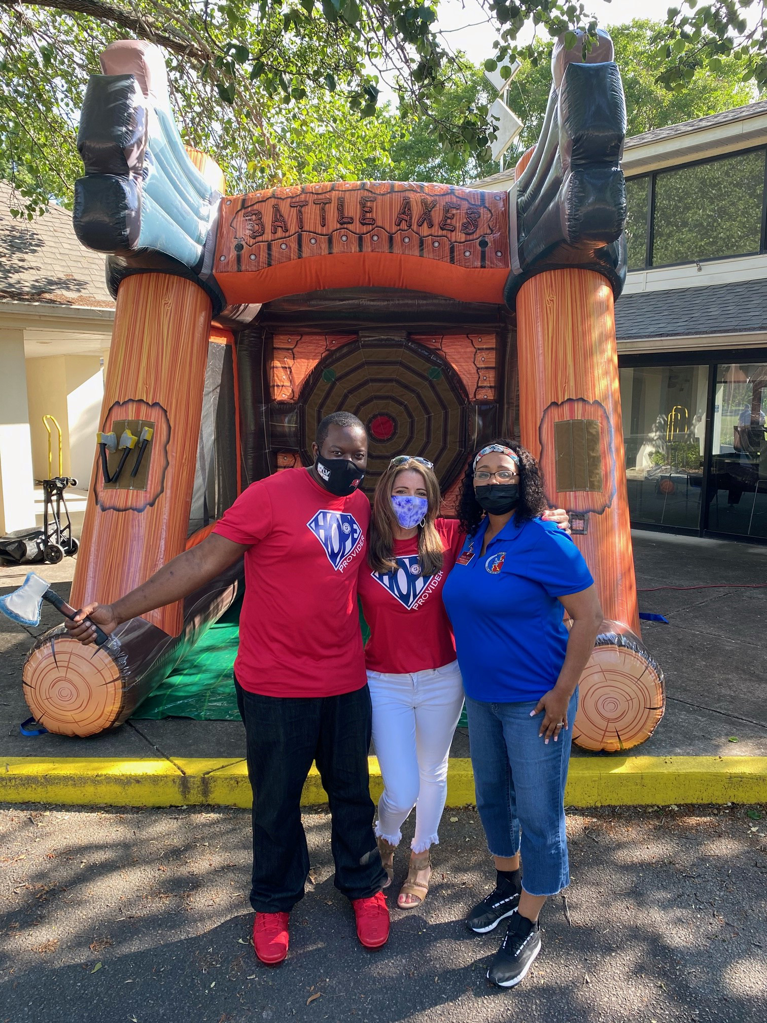 Three people standing in front of Inflatable axe game